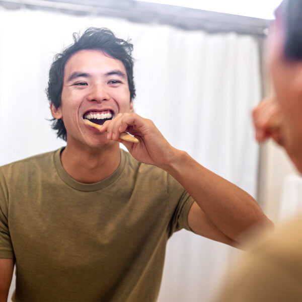 Happy man brushing teeth with Dr. Ginger's Coconut Oil Toothpaste.